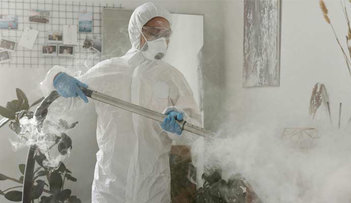 Profesionalac u zaštitnoj odeći čisti parnim čistačem u sobi