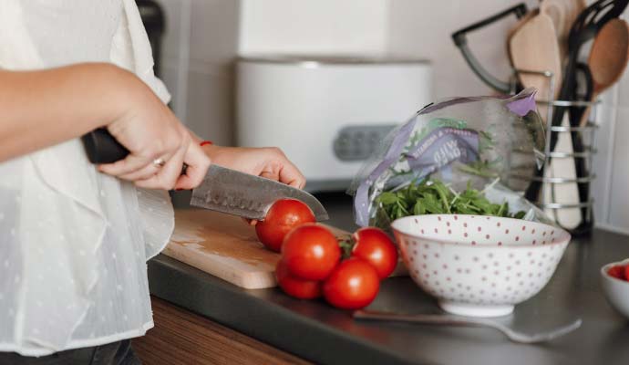 Žena seče paradajz na dasci