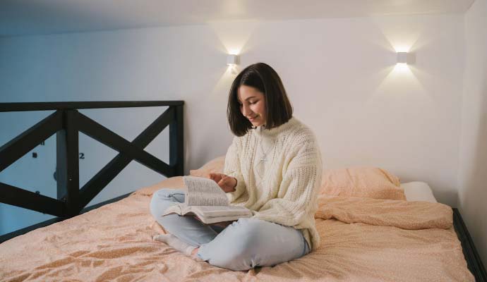 Devojka čita knjigu na sofi u stanu