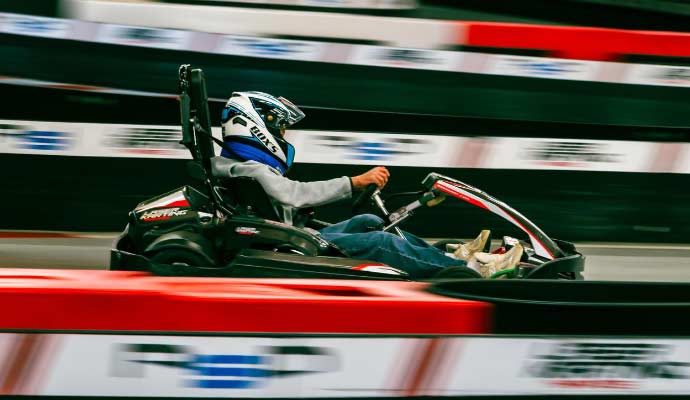 kart-kaciga-trkacka-staza Osoba sa kacigom vozi kart pored crveno-bele zaštitne ograde trkačke staze